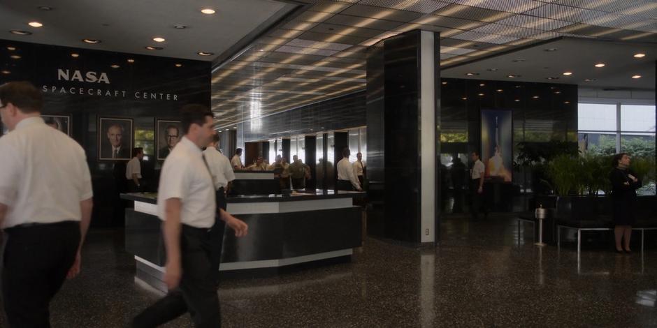 The astronauts races past the elevators and through the lobby towards their cars.