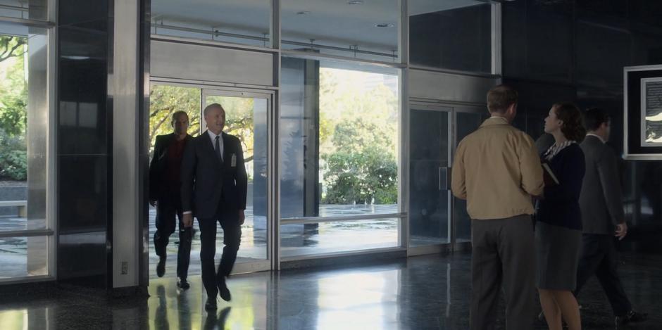 Von Braun smiles while entering the lobby with Deke.