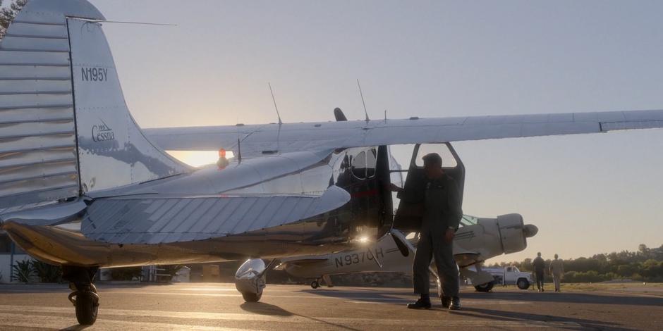 Gordo stands next to his plane and offers a hand to help Tracy out.