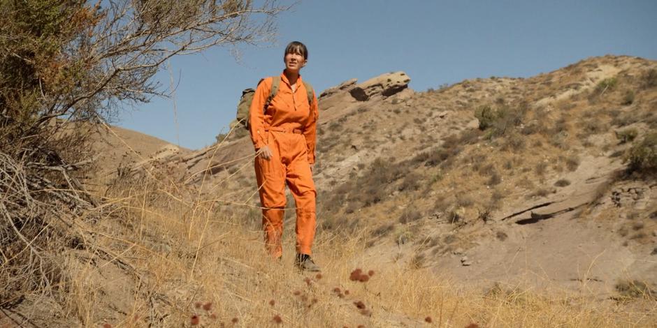 Patty glances up at the harsh sunlight as she treks across the desert.