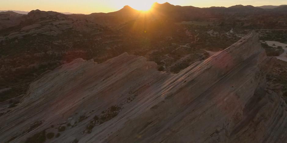 The sun begins to set over the mountains in the distance.