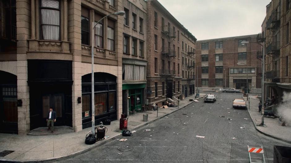 Chase emerges from the doorway alone on a rundown street.