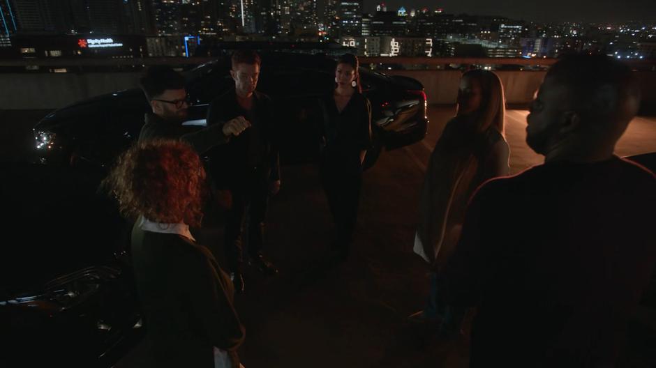 Stacey, Dale, Victor, Tina, Leslie, and Geoffrey stand in a circle discussing the plan.