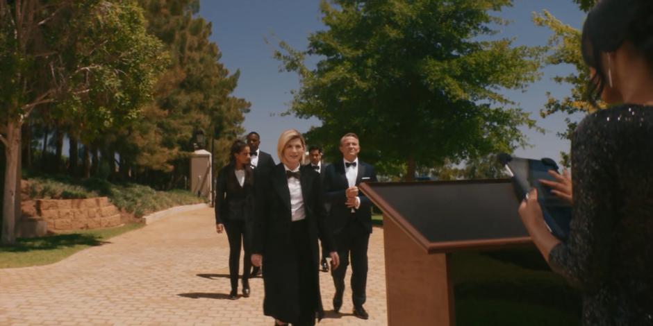 The Doctor leads her fam up to the reception stand.