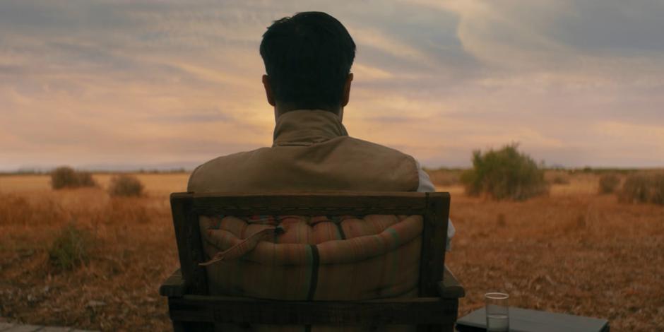 O sits in his chair outside waiting for the Doctor to arrive.