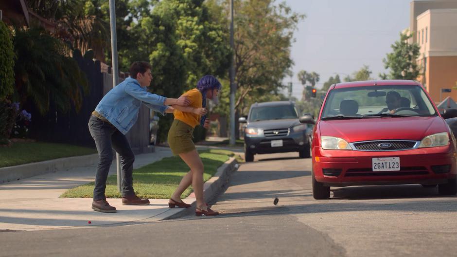 Chase pulls Gert out of the street from in front of a moving car causing her phone to drop to the ground.