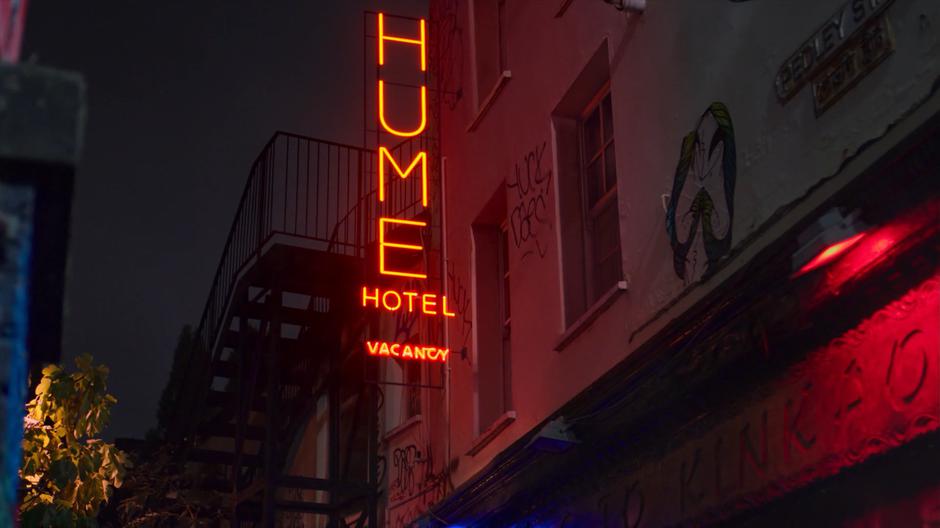 The Hume Hotel neon sign glows above the alley.