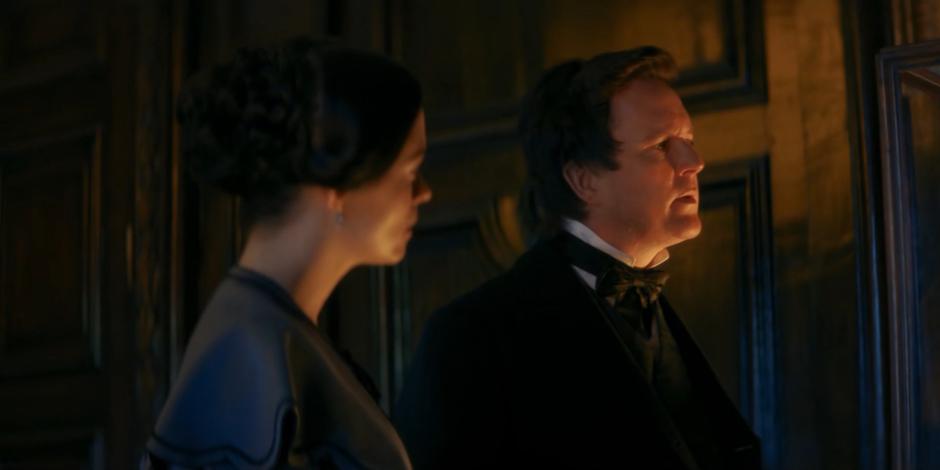 Ada and Babbage watch while the Doctor examines the figure.