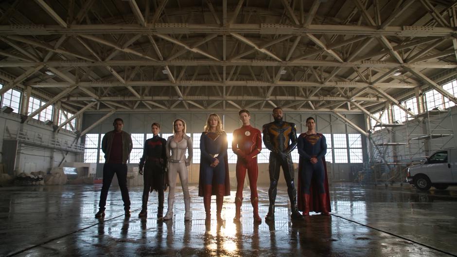 J'onn, Kate, Sara, Kara, Barry, Jefferson, and Clark stand in front of Oliver's memorial.