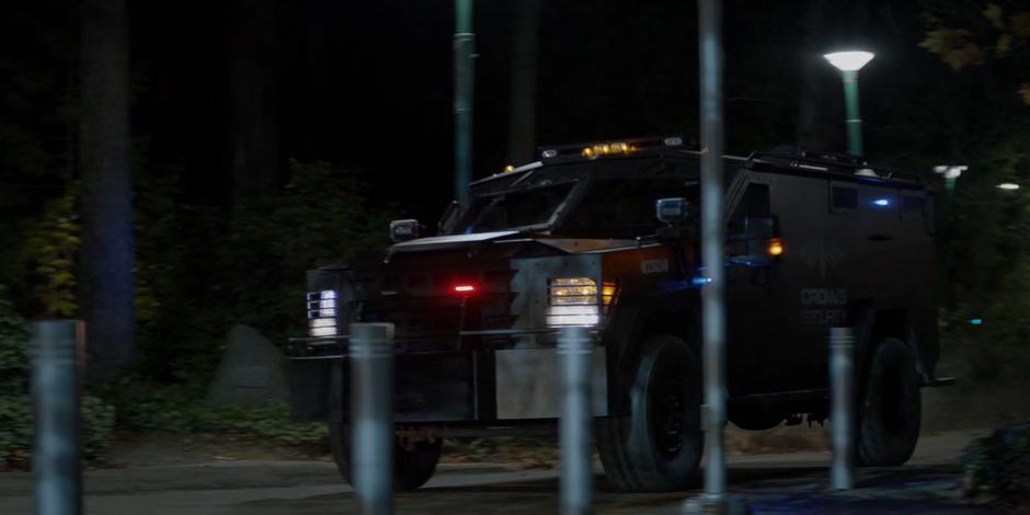 A Crows Security armored truck pulls up in front of the school with its lights shining.