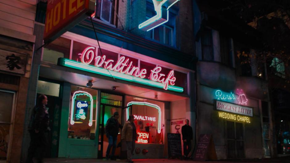 Establishing shot of the front of the cafe as two people exit onto the street.