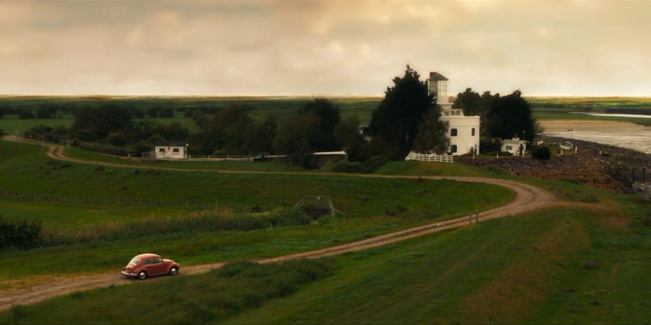 Ruth drives her Beetle down the dirt road to the lighthouse.