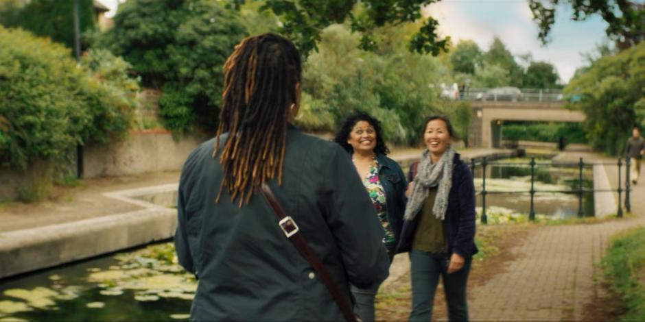 Two people smile at Ruth as she walks past them.