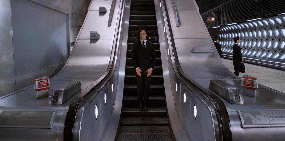 M rides the escalator down into the New York subway station.