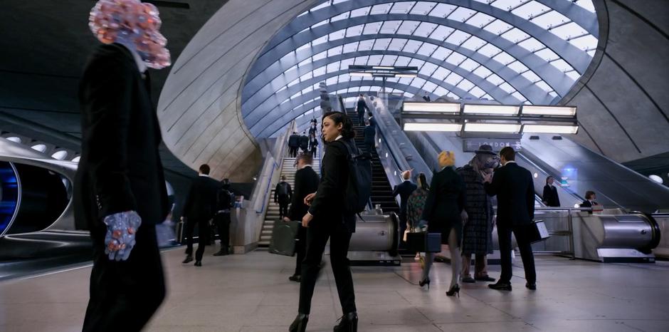 M looks around the busy platform after arriving in London.