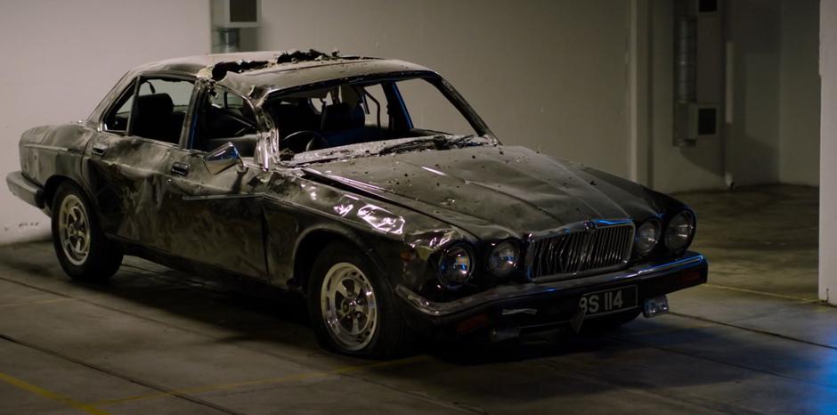 H's destroyed old car sits parked in the garage.