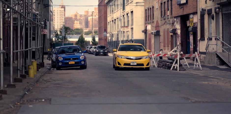 A taxi drives Molly down the street to where she predicted an alien landing.