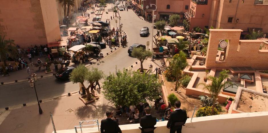 Several M.I.B. agents line the rooftop while more arrive in cars to search the market.