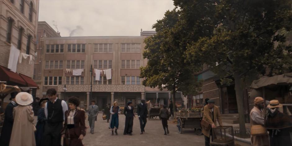 Graham, the Doctor, Yaz, and Ryan walk down the street as Nikola Tesla and Dorothy Skeritt walk ahead of them.