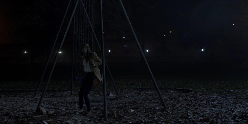 Beth looks over from where she is sitting on the swingset as she sees Kate approaching.