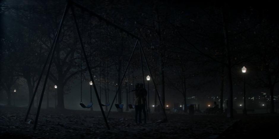 Kate and Beth hug by the swingset at night.