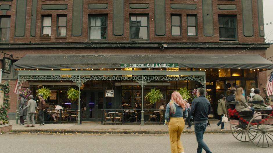 People pass by as Jordan and Maggie sit in the outside dining area of the restaurant.