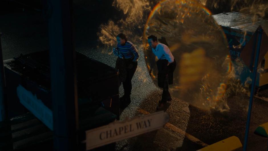 Maggie and Harry appear from a portal in the parking lot of the store.