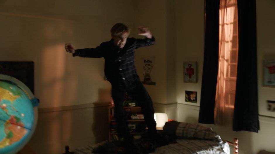The possessed kid jumps down onto his bed after crawling along the walls.