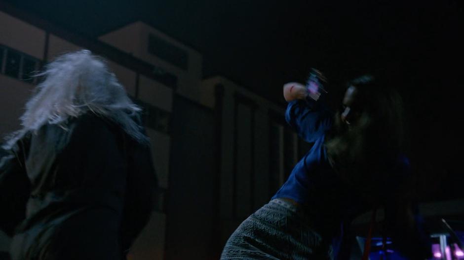 Zari leaps back as the killer slashes at her with a knife.