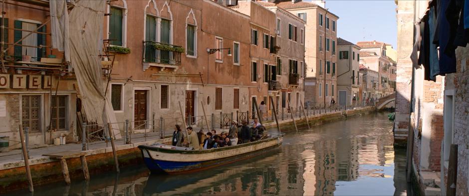 The boat carrying the tour group pulls up in front of the hotel covered in scaffolding and tarps.