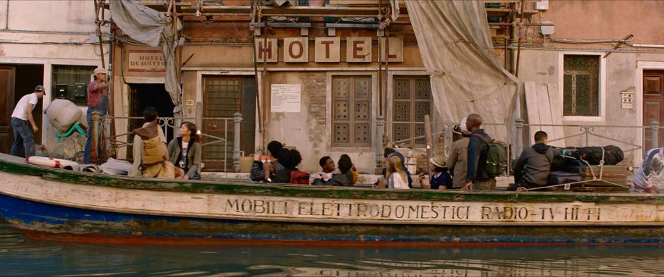 The students and their teachers look up from the boat to their hotel as workers work on the facade.