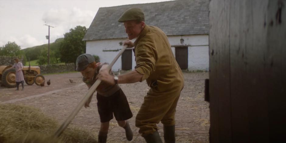 Meg works on a tractor in the background while Patrick shows young Brendan how to move some hay.