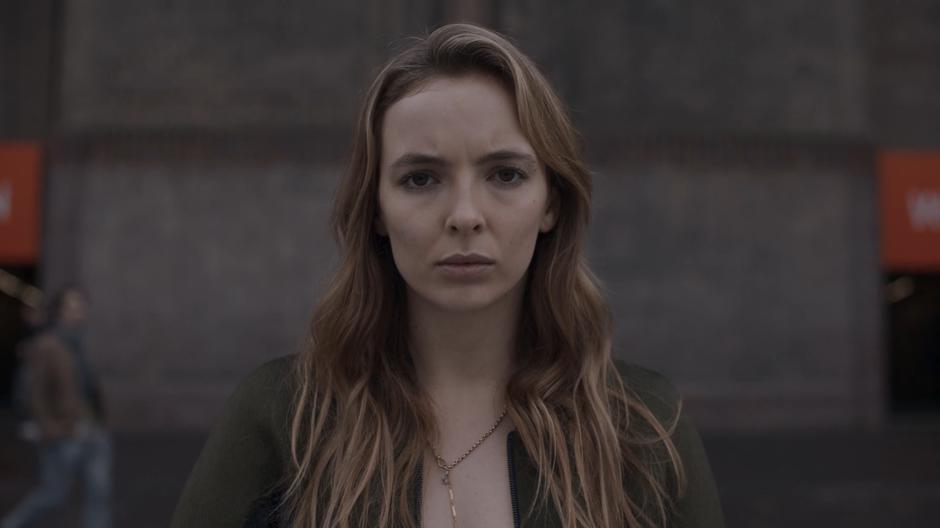 Villanelle stares at a human statue.