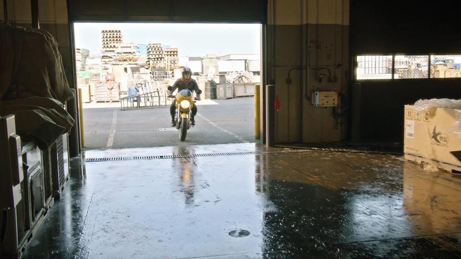 Nate rides into the warehouse on his motorcycle.