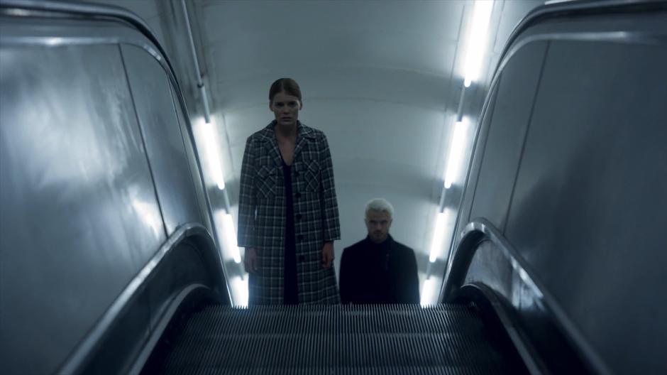 Myfanwy rides the escalator out of the station with Gestalt keeping an eye on her.