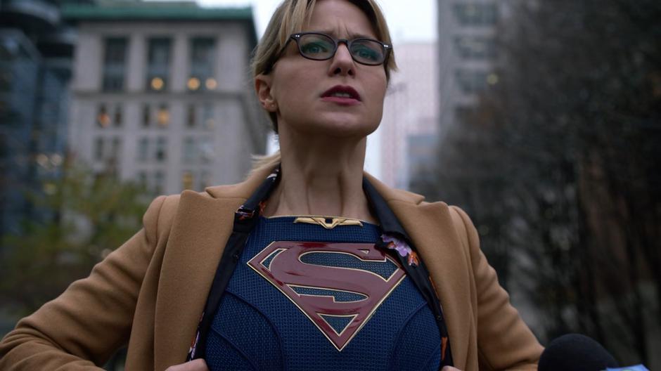 Kara opens her shit to reveal her Supergirl suit underneath.