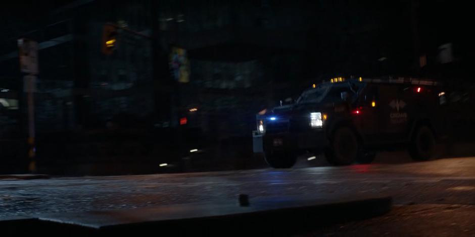 An armored Crows Security truck drives down the street to the front of the building.