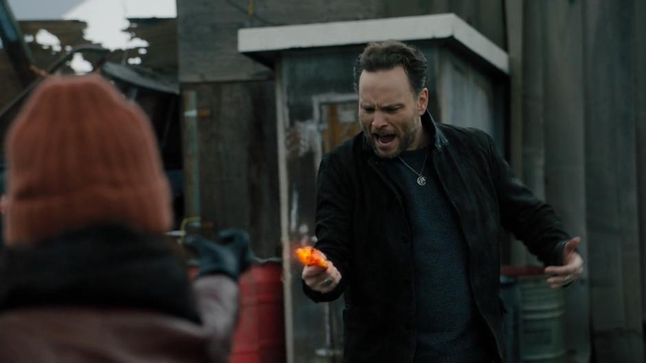 Bruce screams as the gun in his hand is turned red hot by Mel.