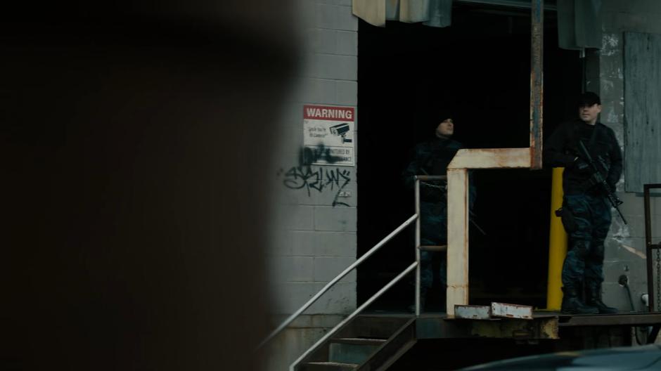 Two guards stand outside the door to the storage facility.