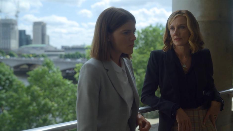 Myfanwy and Lind lean their backs against the railing while they talk.