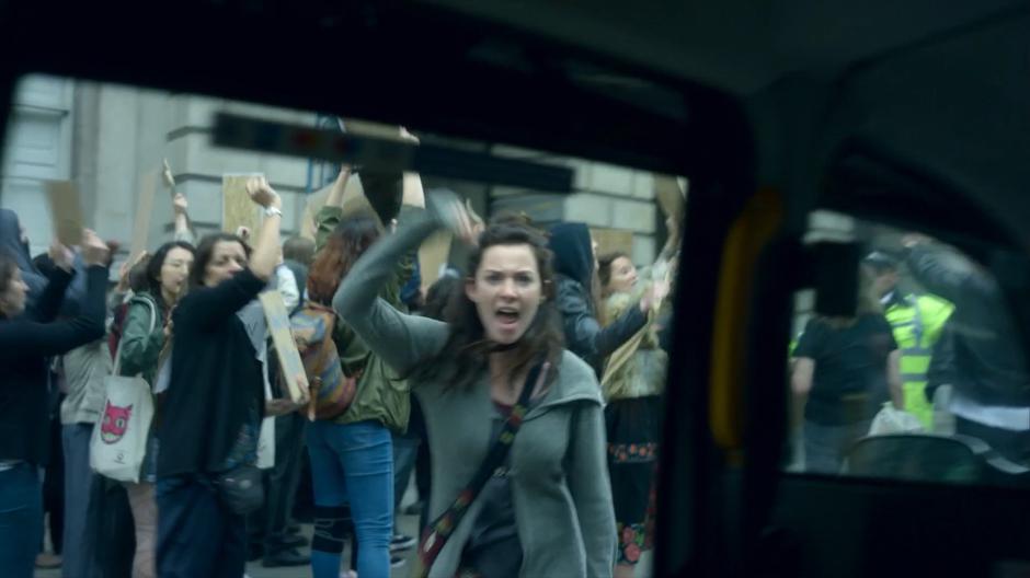 A woman yells at Myfanwy taxi as it drives towards the front gate past a group of protestors.