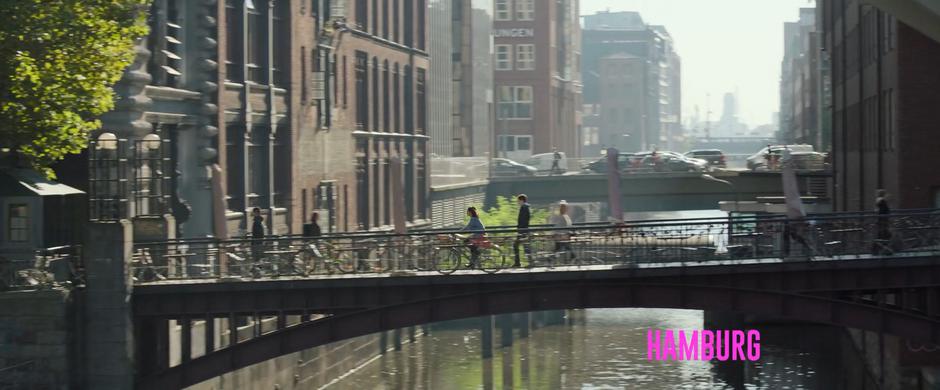 Elena rides her bike across a pedestrian bridge.