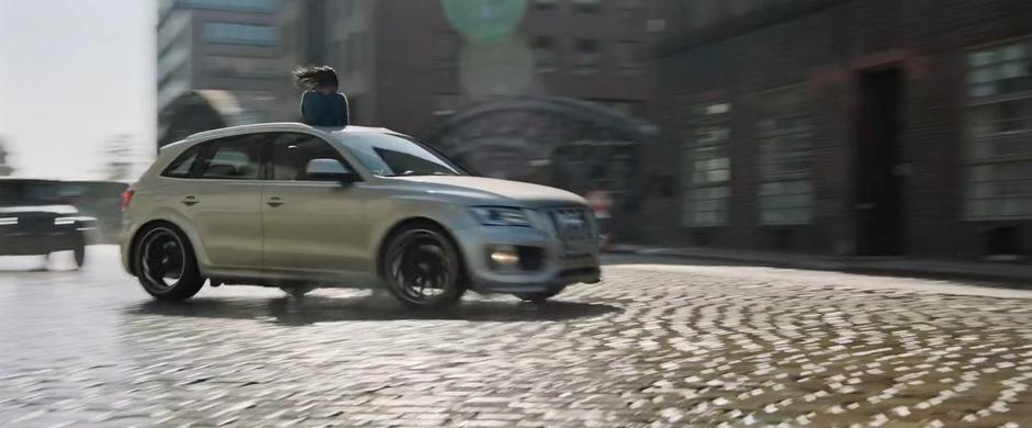 The two vehicles race around the corner with Jane standing out of the sunroof.