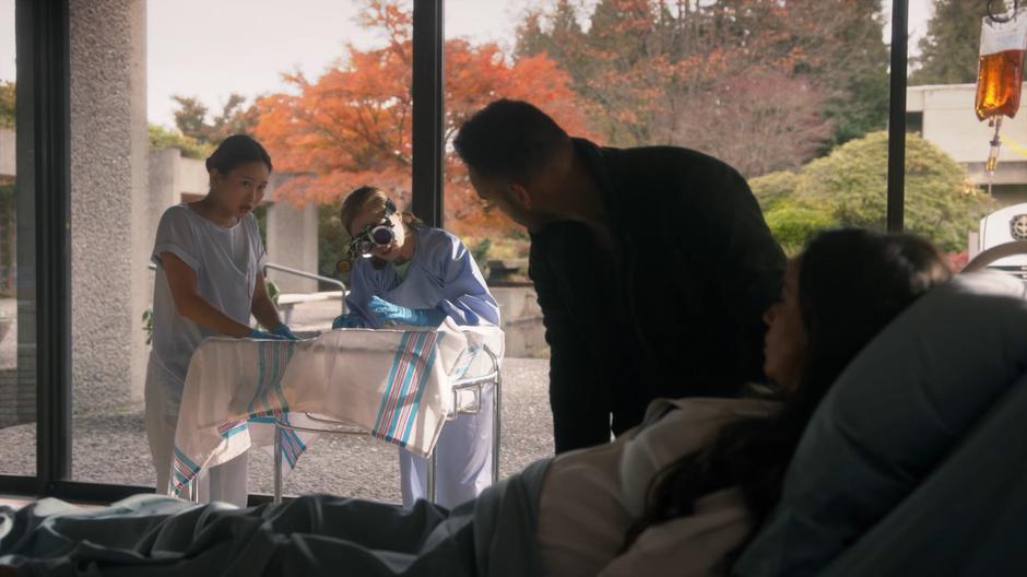 Penny and Julia look over at Professor Lipson and Healer Faye as they prepare for the operation.