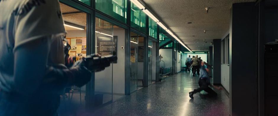 People flee as Harley shoots grenades at officers in the hallway.