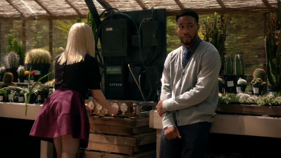 Hamish Bax leans against the table while Alice messes with the circumstances control panel.