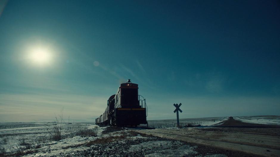 The train approaches a remote rail crossing.