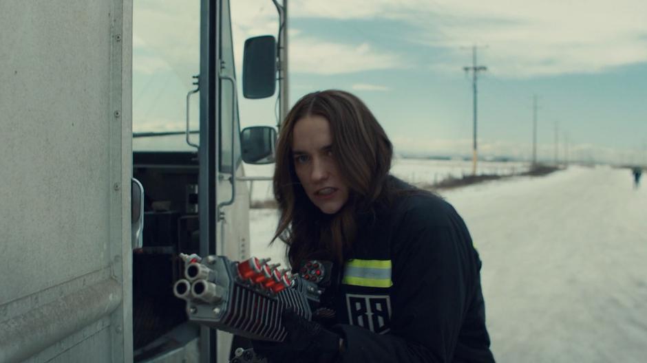 Wynonna steps out of the truck with her fancy new gun ready while the driver runs down the road behind her.