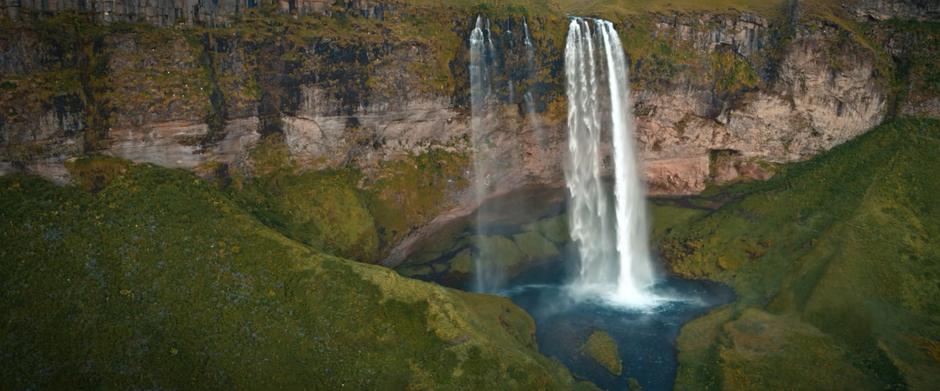 Water flows off a cliff into a small basin.