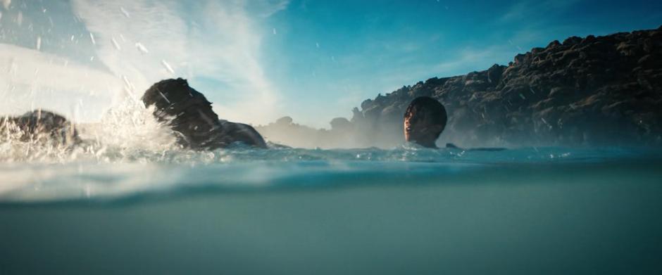 Booker and Michael swim to shore after teleporting into the water.